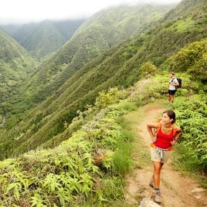 A couple hikers trekking mountain trail on a waterfall local guided hiking tour on Maui.