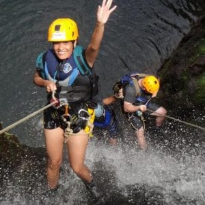 Couple rappelling down a waterfall on Maui